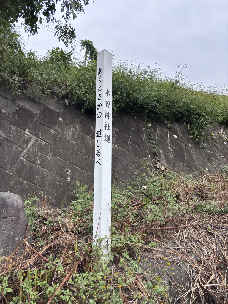 「木曽神社道」と書かれた白い柱と、古い道しるべの石